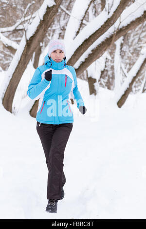 Junge schlanke Frau im Winter Park Joggen. Kaukasische Mädchen in Sportbekleidung ausgeführt Stockfoto