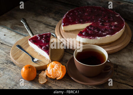 Keil des klassischen New York Stil Käsekuchen mit Tasse Tee und Mandarinen, hausgemachte Backwaren Rezept oder Menü-Hintergrund Stockfoto