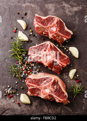 Rohe frische Lende Lammkoteletts mit Kräutern und Gewürzen auf Stein Schiefer Teller Stockfoto