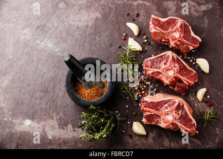 Rohe frische Lende Lammkoteletts mit Kräutern und Gewürzen auf Stein Schiefer Teller Stockfoto