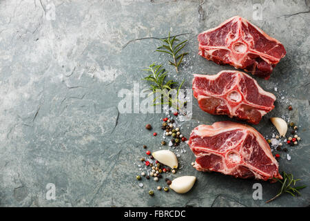 Rohe frische Lende Lammkoteletts mit Kräutern und Gewürzen auf Stein Schiefer Teller Stockfoto