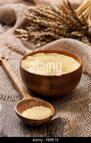 Couscous in einer Holzschale auf einem hölzernen Hintergrund und Entlassung Stockfoto