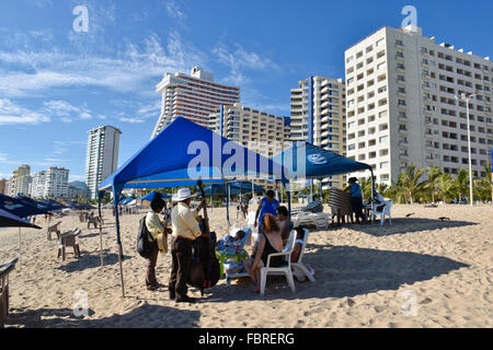 Mariachi Sänger und Musiker spielen für Touristen am Papagayo Strand in Acapulco, Mexiko Stockfoto