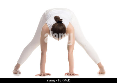 Sportlich schöne junge Anfang Yoga Schüler Frau in weißen Sportbekleidung Stuhlposition nach vorne beugen, Prasarita Padottanasana zu tun Stockfoto