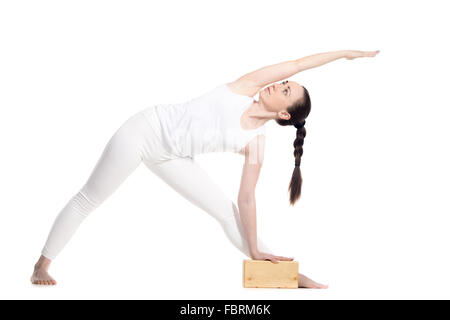 Sportlich schöne junge Anfang Yoga Studentin in Utthita Trikonasana, erweitert Dreieck darstellen stützte sich auf yogische stehen Stockfoto