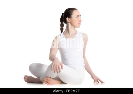 Sportlich schöne junge Frau in weißem Sportbekleidung Yoga zu praktizieren, im Revolved einfache Pose, spinal Twist Schneidersitz sitzen Stockfoto