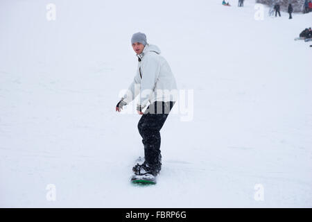 Einziger Mann im weißen Kittel und grauen Hut schieben bergab auf Snowboard im Winter im Skigebiet Stockfoto