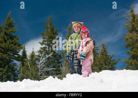 Junge Geschwister stehen zusammen im Schnee Stockfoto