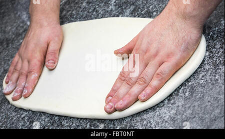 Detail der Hände machen die Pizza auf einem Tisch. Stockfoto