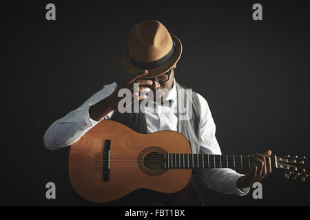 Eleganter junger Mann in intelligente Kleidung und Hut mit Gitarre Stockfoto