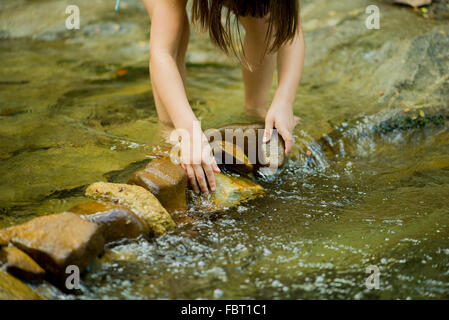 Kind mit Felsen zum Bau eines Staudamms in einem seichten Bach Stockfoto