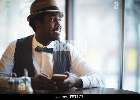 Eleganter junger Mann in Hut und intelligente Kleidung sitzen im café Stockfoto