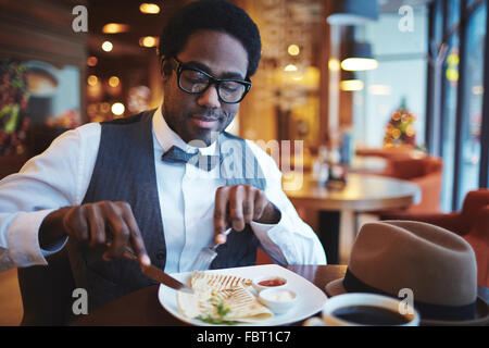 Eleganter junger Mann Essen im café Stockfoto