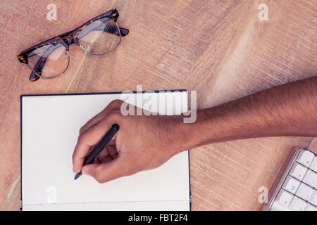 Geschäftsmann schreiben auf Notebook von Brillen am Schreibtisch Stockfoto