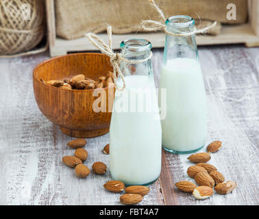 Mandel-Milch in Flaschen mit Mandel Muttern auf hölzernen Hintergrund Stockfoto