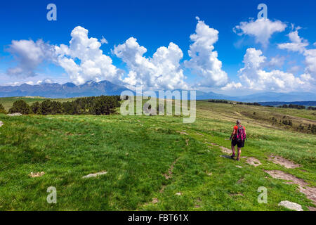 Weibliche Walker mit roten Rucksack auf Wanderweg mit Cumulus-Wolken Stockfoto