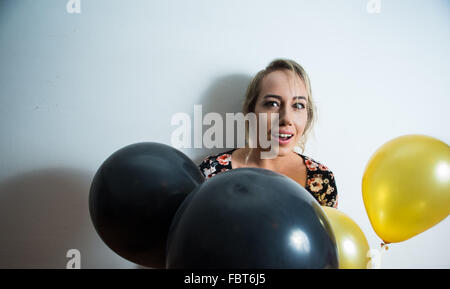 Schönes Modell, weiße Wand gelehnt und spähen losziehst aus Luftballons Stockfoto