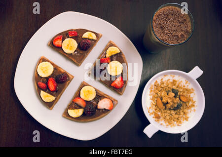 Pfannkuchen, schneiden Sie in vier Teile, dekoriert mit Früchten, Glas kalter Kaffee trinken und Joghurt Müsli bowl Stockfoto