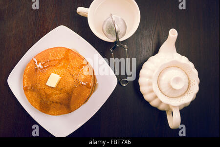 Tasse Tee, heißes Wasser Karaffe und Platte mit Pfannkuchen von oben gesehen Stockfoto