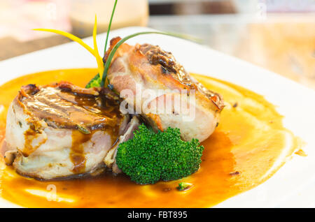 Köstliches Filet Steak, eingewickelt in Speck und perfekt zubereitet, auf orange Platte mit einigen pflanzlichen Elementen, elegante Präsentation gelegt Stockfoto