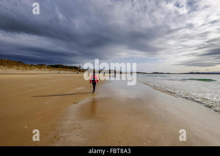 Frau zu Fuß entlang der wunderschönen Camusdarach Strand in den schottischen Highlands in der Nähe von Fort William und Mallaig Stockfoto