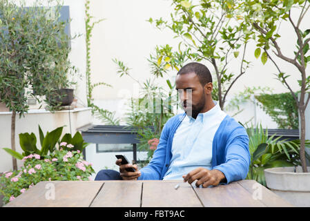 Mann sitzt am Tisch im Innenhof Anruf tätigen Stockfoto