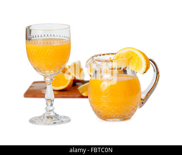 Geschliffenes Glas isoliert, Becher und gefüllt mit frisch gepresstem Orangensaft mit Orangenscheibe am Rand der Kanne Krug Stockfoto