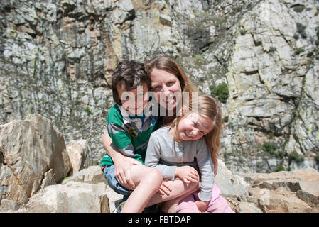 Mutter und Kinder sitzen auf Felsformation, Porträt Stockfoto