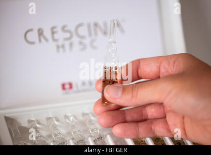 Frau Hand mit Ampulle von Crescina Re-Growth vor Crescina HFSC 100 % komplette Behandlungsbox. Stockfoto