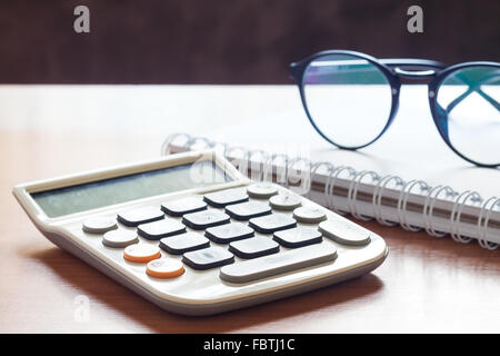 Taschenrechner mit Brille auf Holztisch, Fotoarchiv Stockfoto