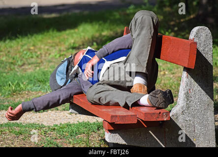 Obdachloser schläft auf einer Parkbank in der Stadt Stockfoto