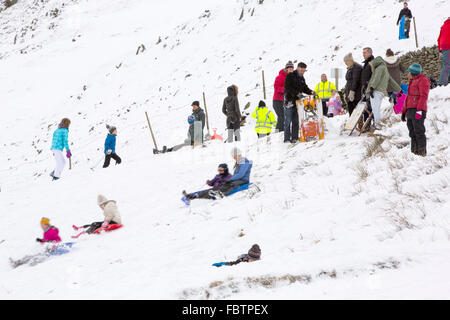 Familien Schlitteln auf Kirkstone Pass im Lake District im Winter, UK. Stockfoto