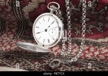 Silberne Taschenuhr auf Teppich Stockfoto