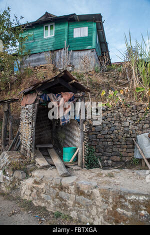 Blaue Holzhaus auf einem Hügel mit offenen zweiflügeliger drapierten Plumpsklo im Vordergrund. Main Street, Touphema, Nagaland, Indien Stockfoto
