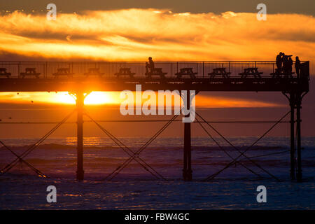 Aberystwyth Wales UK, Dienstag, 19. Januar 2016 am Ende einen klaren kalten Wintertag, Leute zu beobachten die Stare von Aberystwyth Pier Sonnenuntergang über Cardigan Bay im Westen Wales Credit: Keith Morris/Alamy Live-Nachrichten Stockfoto