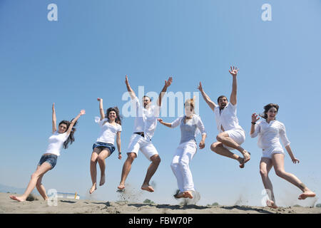 glückliche Menschengruppe haben Spaß und läuft auf Strand Stockfoto
