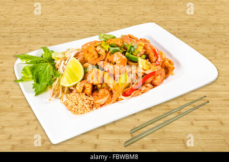 Chinesische Fischfutter auf einem weißen Teller mit Shrimps, Hühnerfleisch, Sojasprossen, Gemüse und Salat. Hintergrund-Holz, Stäbchen. Stockfoto