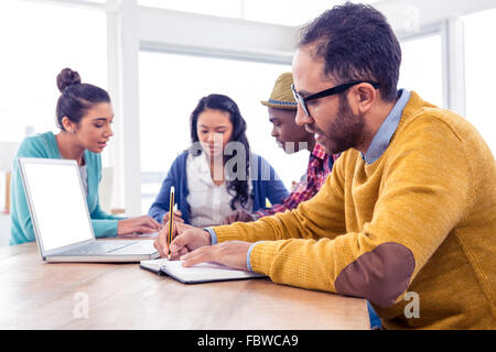 Business-Mann, sitzend mit Kollegen in Buch schreiben Stockfoto