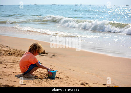 Einen kleinen Jungen mit Sand zu spielen. Stockfoto