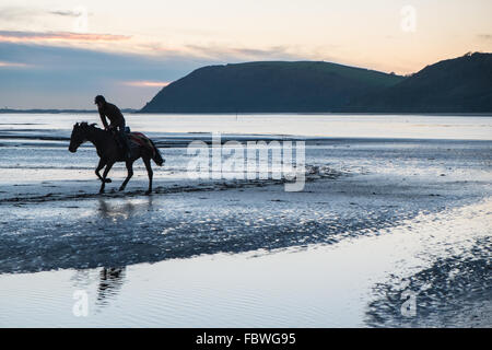 Ferryside Strand, Carmarthenshire, Wales, UK. 19. Januar 2016. Nach tagelangem Regen an einem klaren sonnigen Tag bei Sonnenuntergang/Sonnenuntergang. Obwohl bitterkalt galoppiert ein Jockey sein Pferd am leeren Strand von Ferryside,Carmarthenshire,Wales,U.K Credit: Paul Quayle/Alamy Live News Stockfoto