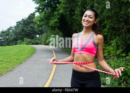 Junge Frau misst ihre Taille Stockfoto