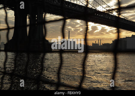 Industriellen Blick auf Manhattan Bridge am Wasser Sonnenaufgang New York City durch einen Drahtzaun verzerrt Stockfoto