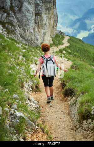 Frau Wanderer mit Rucksack Materialseilbahn auf einem steilen Weg in den Bergen Stockfoto