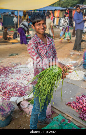 Indischer Markt. Junger Junge verkauft Zwiebeln auf dem sehr großen und sehr lebendigen Balipara Saturday Market, Assam, Indien. Stockfoto