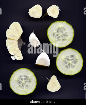 Gurkenscheiben und Knoblauchzehen auf schwarz Stockfoto