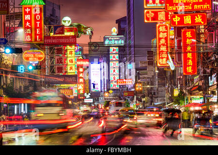 Verkehr auf Yaowarat Straße verläuft unter beleuchteten Zeichen im Stadtteil Chinatown in der Abenddämmerung in Bangkok, Thailand. Stockfoto