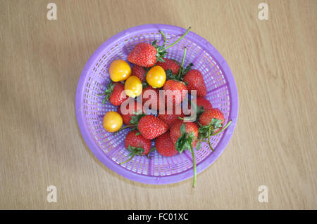 Frische Erdbeeren und Kap-Stachelbeere im Kunststoffkorb Stockfoto