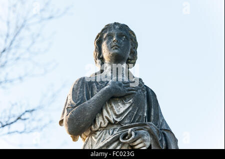 Statue auf einem Friedhof, Mädchen mit der Hand auf dem Herzen Stockfoto