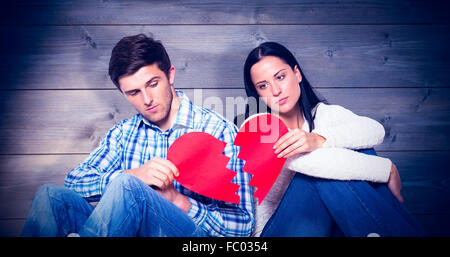 Zusammengesetztes Bild des jungen Paares sitzen auf Boden mit gebrochenen Herzen Stockfoto