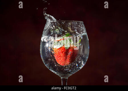 frische Erdbeeren Tropfen in Wasser, enthalten im Weinglas, Spritzen Stockfoto